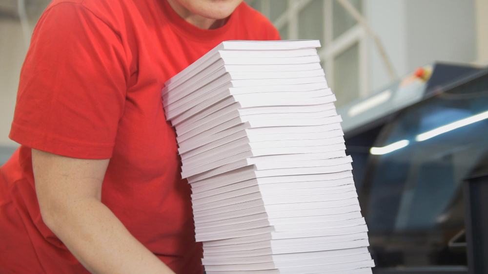 Hands of Female Worker Folds a Paper Stacks in Typography