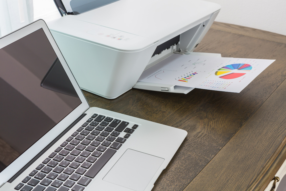 Laptop on a Wooden Table With a Printer 